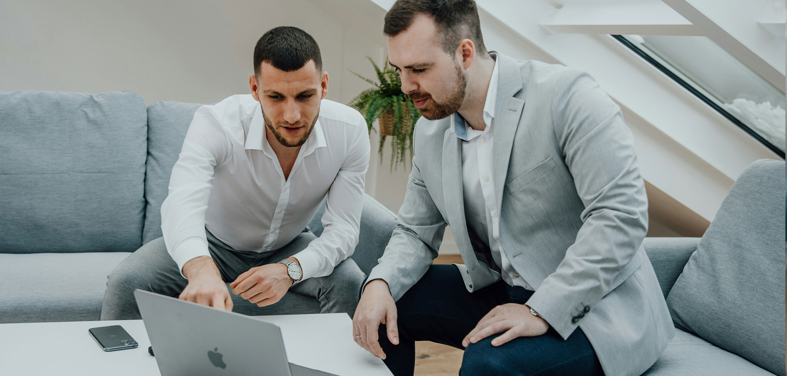 Two guys sitting at a laptop in an office